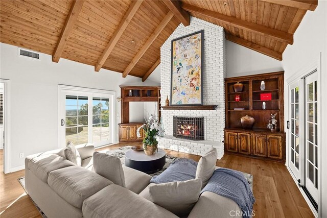 living room featuring beam ceiling, a brick fireplace, and wooden ceiling