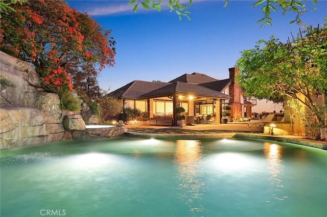 pool at dusk featuring a patio area and outdoor lounge area