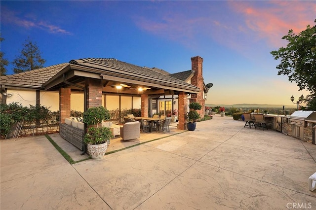 patio terrace at dusk featuring an outdoor kitchen