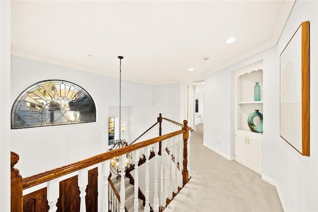 hallway with ornamental molding, light colored carpet, and built in shelves