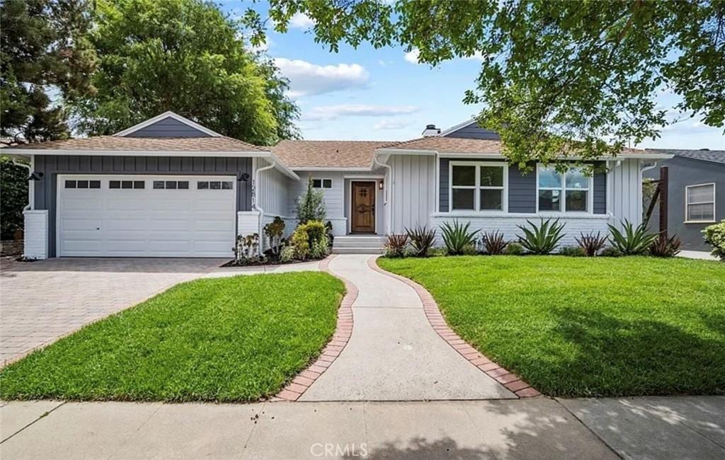 ranch-style home with a front lawn, decorative driveway, board and batten siding, a garage, and brick siding