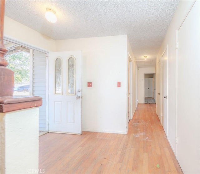 foyer entrance with a textured ceiling and light hardwood / wood-style flooring