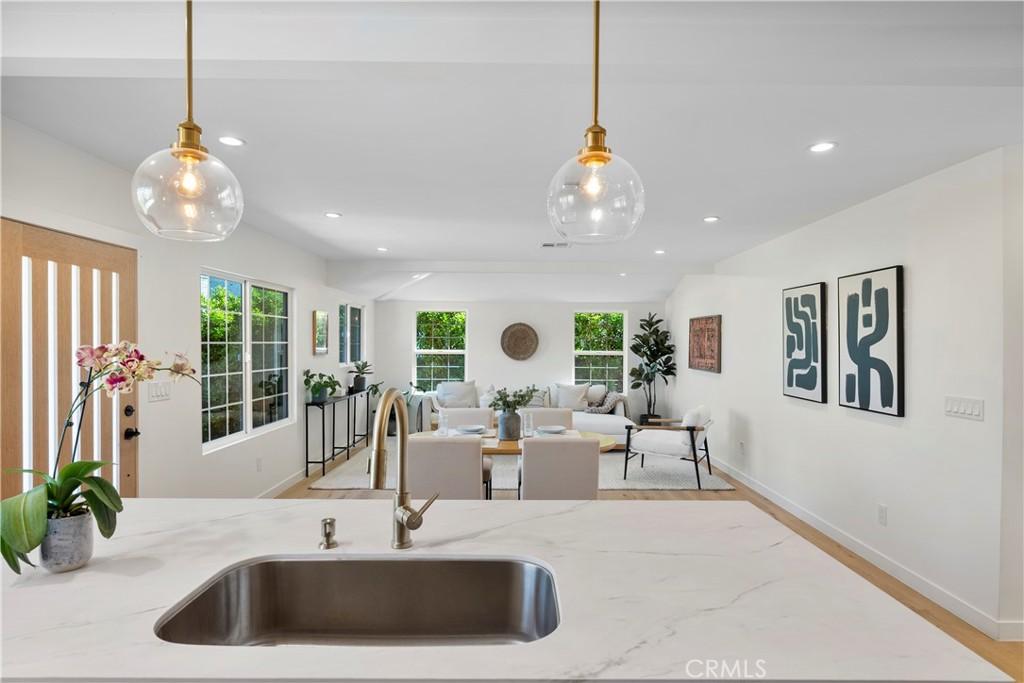 kitchen featuring hanging light fixtures, light stone countertops, sink, and a wealth of natural light