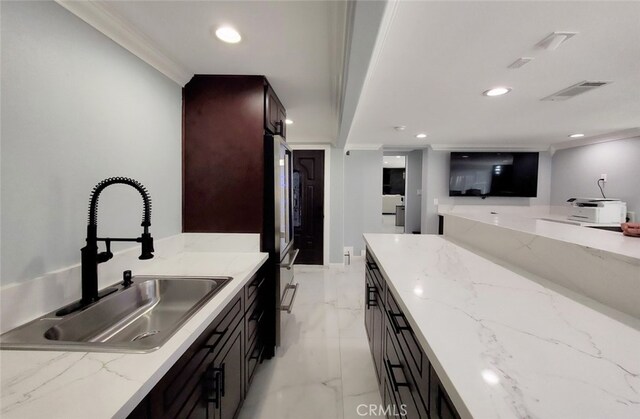 kitchen with light stone counters, sink, and ornamental molding