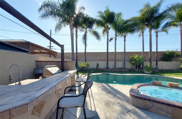 view of pool with an in ground hot tub, a bar, a patio, and grilling area