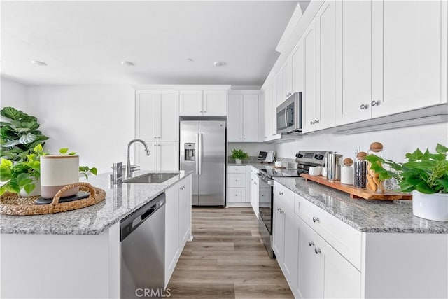 9431 N Sepulveda Blvd Unit 3, North Hills, CA 91343 - kitchen with stainless steel appliances, white cabinets, light wood-style floors, and light stone countertops