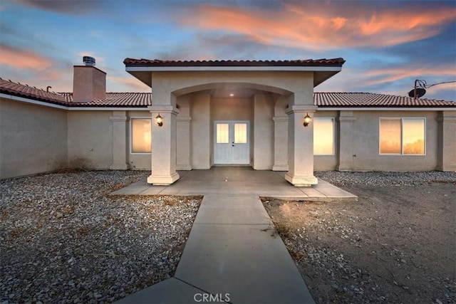 back house at dusk featuring french doors