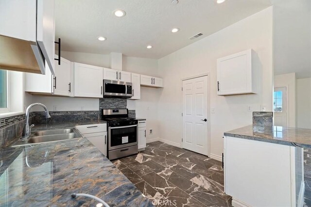 kitchen featuring appliances with stainless steel finishes, tasteful backsplash, white cabinetry, sink, and kitchen peninsula