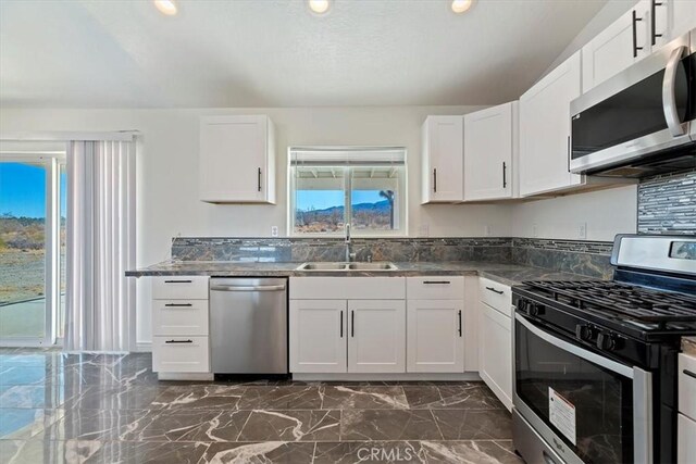 kitchen with tasteful backsplash, sink, white cabinets, and appliances with stainless steel finishes