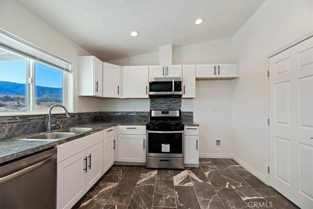 kitchen with lofted ceiling, sink, a mountain view, stainless steel appliances, and white cabinets