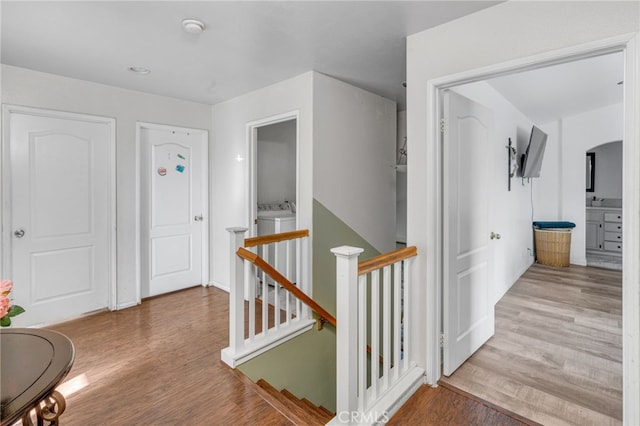 corridor with separate washer and dryer and light hardwood / wood-style floors