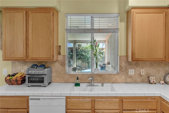 kitchen with dishwasher, tasteful backsplash, tile counters, and sink