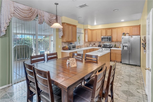 kitchen with sink, hanging light fixtures, light brown cabinetry, tasteful backsplash, and stainless steel appliances