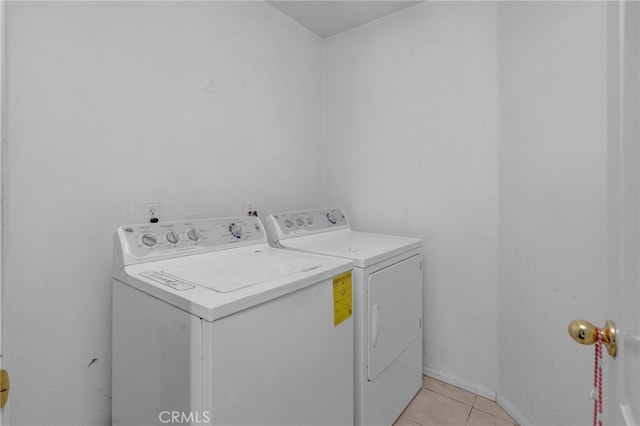 clothes washing area with washer and clothes dryer and light tile patterned floors