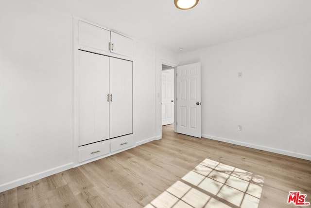 unfurnished bedroom featuring light wood-type flooring and a closet