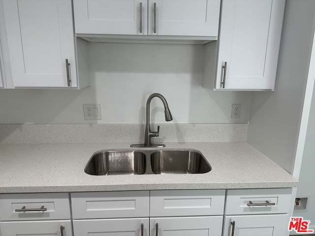 kitchen with white cabinets, light stone countertops, and sink