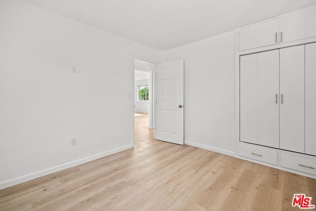 unfurnished bedroom with light hardwood / wood-style floors and a closet