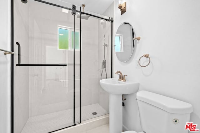 bathroom featuring toilet, a shower with shower door, and sink