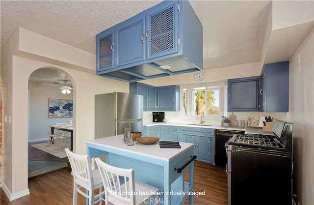 kitchen with blue cabinets, gas range, ceiling fan, black dishwasher, and dark hardwood / wood-style flooring