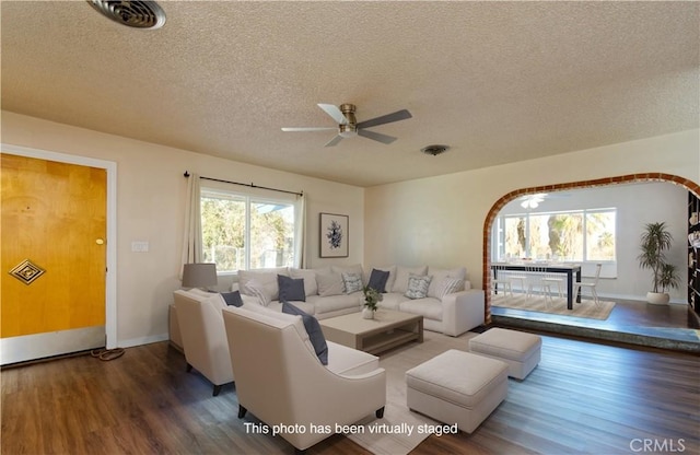 living room featuring ceiling fan, dark hardwood / wood-style flooring, a healthy amount of sunlight, and a textured ceiling