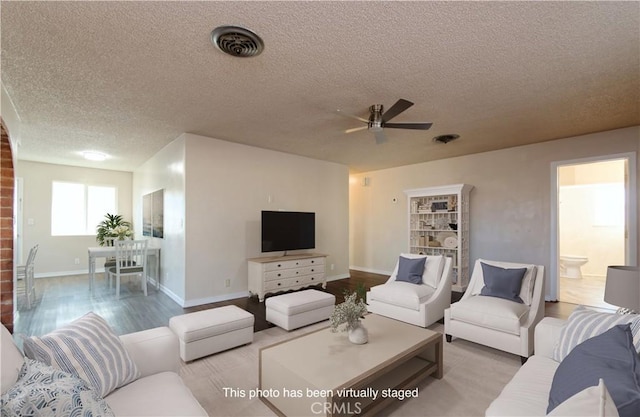 living room with wood-type flooring, a textured ceiling, and ceiling fan