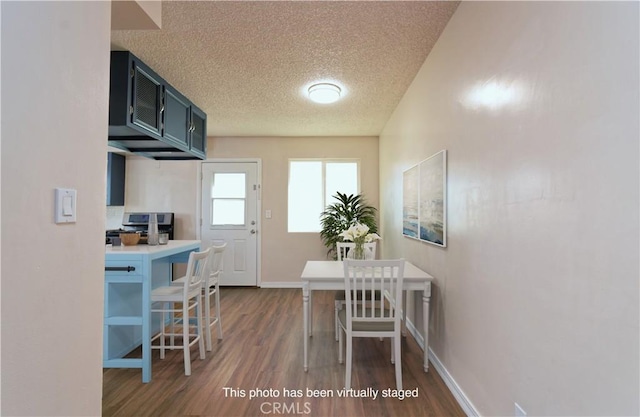 kitchen with a breakfast bar, stainless steel stove, dark wood-type flooring, and a textured ceiling