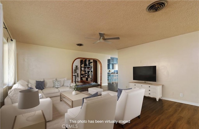 living room with dark hardwood / wood-style floors, ceiling fan, and a textured ceiling