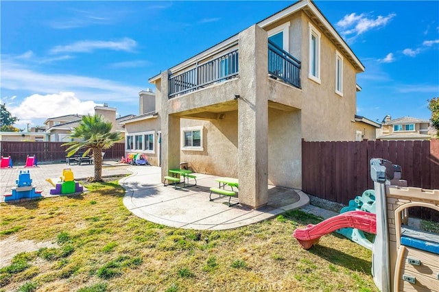 rear view of house with a patio area, a balcony, and a lawn