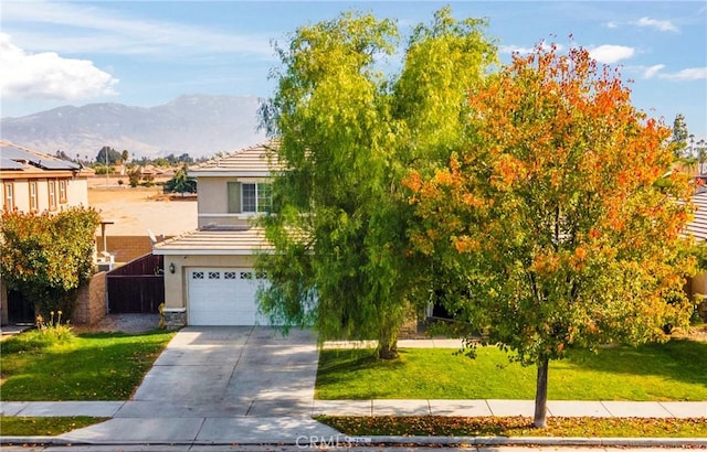 obstructed view of property featuring a garage, a mountain view, and a front lawn