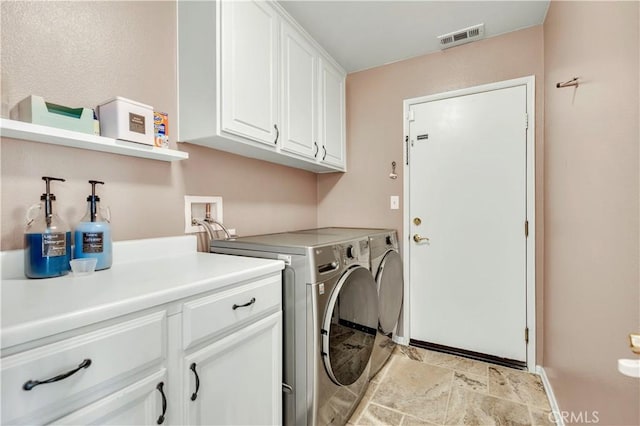 clothes washing area featuring cabinets and washer and dryer