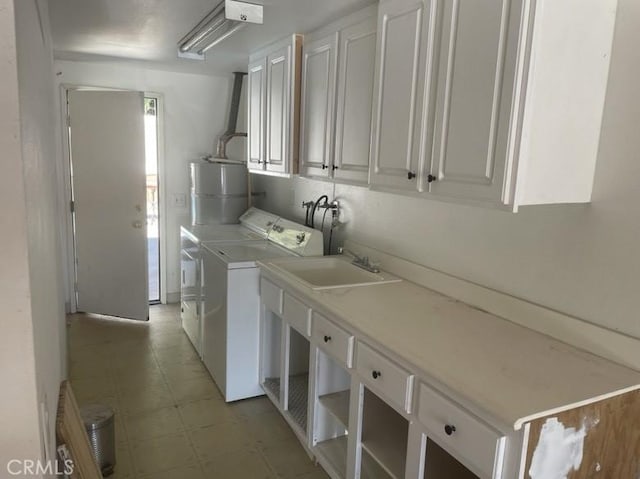 laundry area with washing machine and clothes dryer, sink, cabinets, and water heater