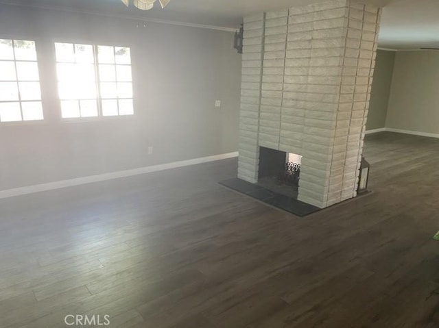 unfurnished living room featuring dark hardwood / wood-style flooring, ornamental molding, and a fireplace