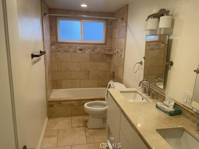 full bathroom featuring tile patterned flooring, vanity, tiled shower / bath combo, and toilet