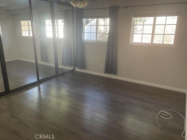 empty room with ceiling fan and dark wood-type flooring