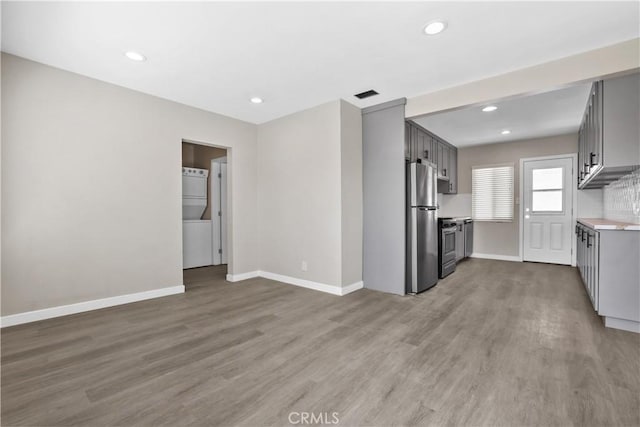 kitchen featuring washer / dryer, gray cabinetry, light hardwood / wood-style floors, and appliances with stainless steel finishes