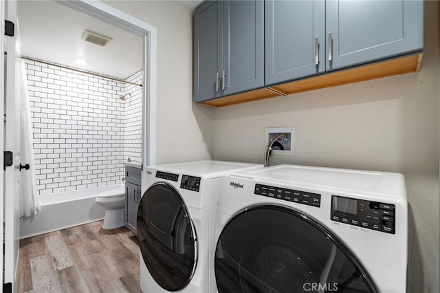 laundry area featuring cabinets, light wood-type flooring, and washer and clothes dryer