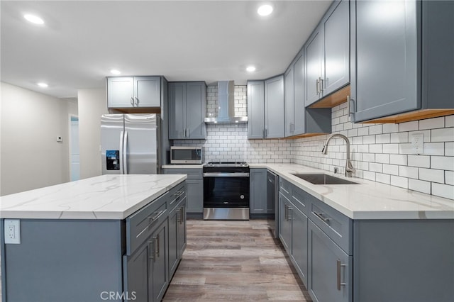 kitchen featuring gray cabinetry, wall chimney exhaust hood, sink, and stainless steel appliances