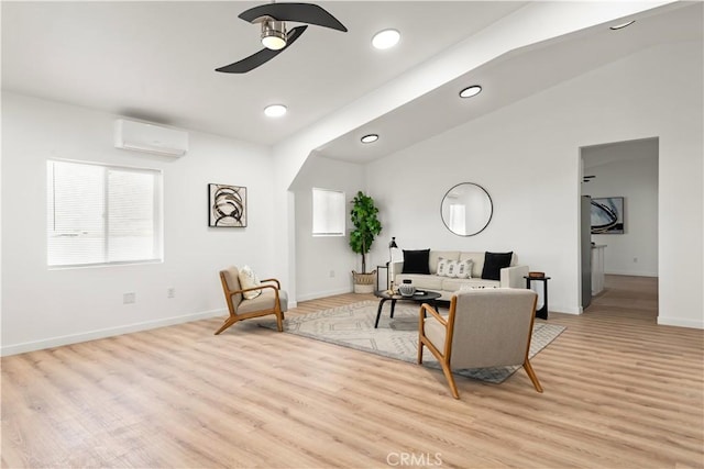 living room with vaulted ceiling, light hardwood / wood-style floors, and a wall mounted air conditioner