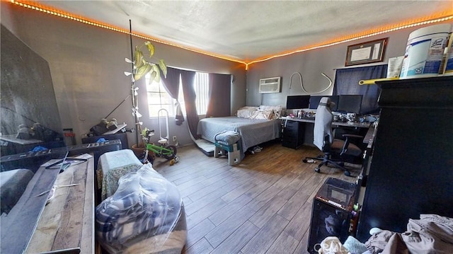 bedroom featuring a textured ceiling, hardwood / wood-style flooring, and a wall mounted AC