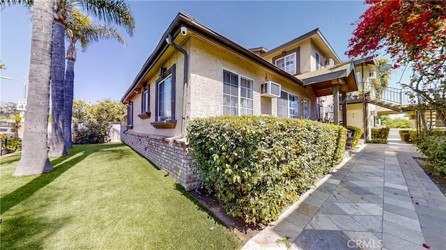 view of property exterior with a wall mounted AC and a yard