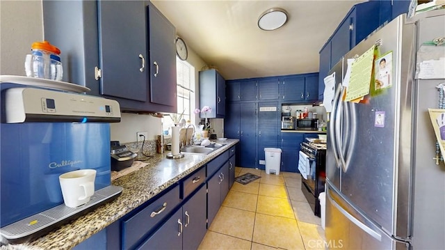 kitchen featuring sink, light tile patterned floors, stainless steel appliances, and blue cabinets