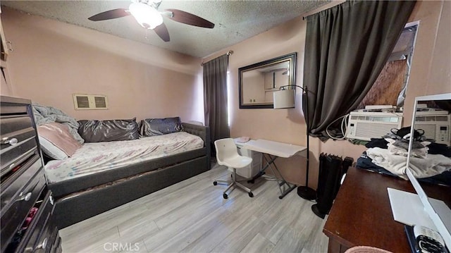 bedroom with a textured ceiling, light hardwood / wood-style flooring, and ceiling fan