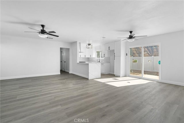 unfurnished living room with ceiling fan, sink, and light wood-type flooring