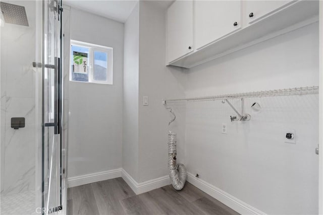 washroom with electric dryer hookup, cabinets, and light wood-type flooring