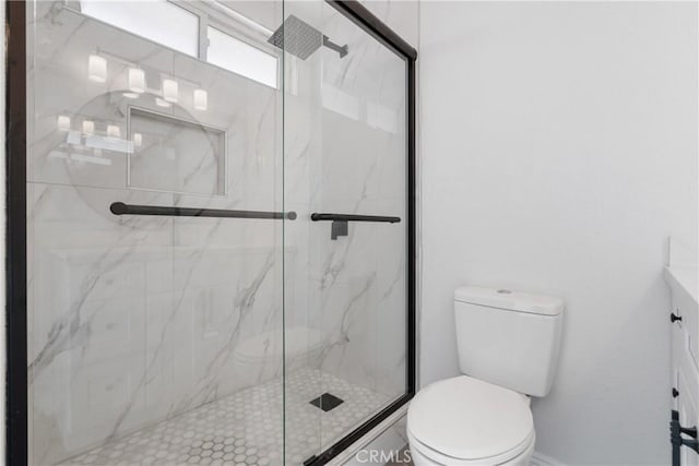 bathroom with a shower with door and toilet