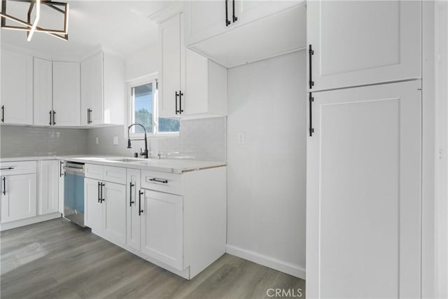 kitchen with decorative backsplash, dishwasher, white cabinets, and light hardwood / wood-style flooring