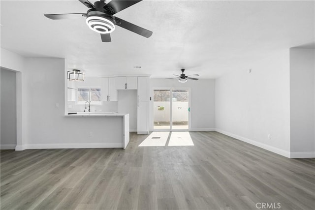 unfurnished living room featuring ceiling fan, light hardwood / wood-style flooring, a healthy amount of sunlight, and sink