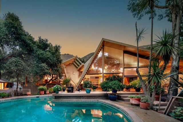 pool at dusk with a patio area