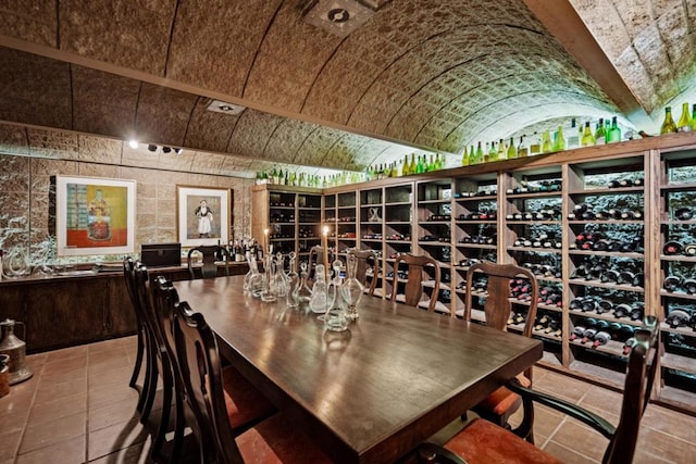 wine area with vaulted ceiling and light tile patterned flooring