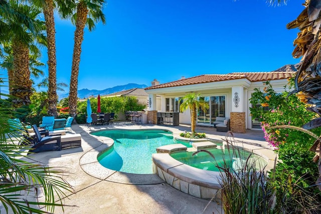 view of swimming pool with a bar, a mountain view, a patio, and an in ground hot tub